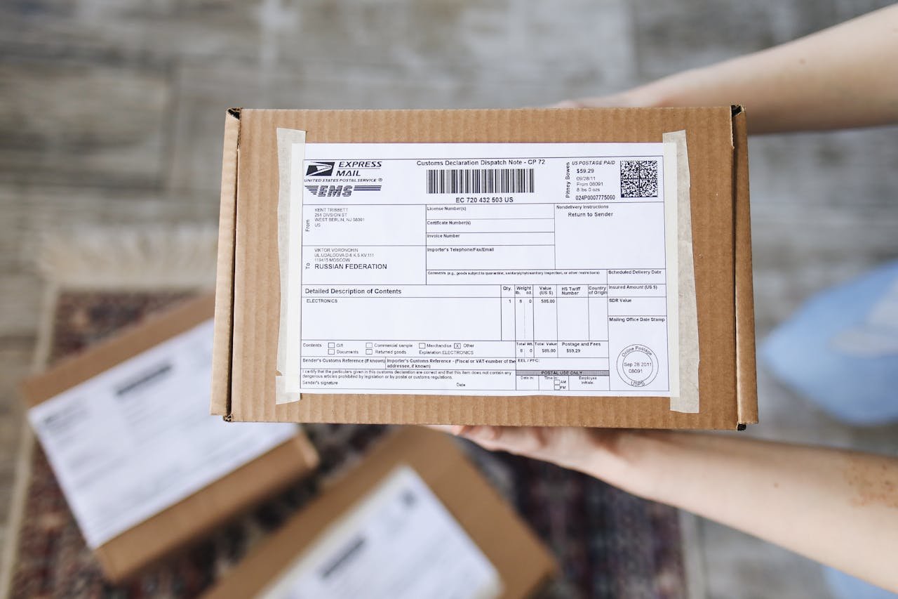 Contacto paquetería Badalona. Top view of hands holding an express mail parcel with a customs declaration.